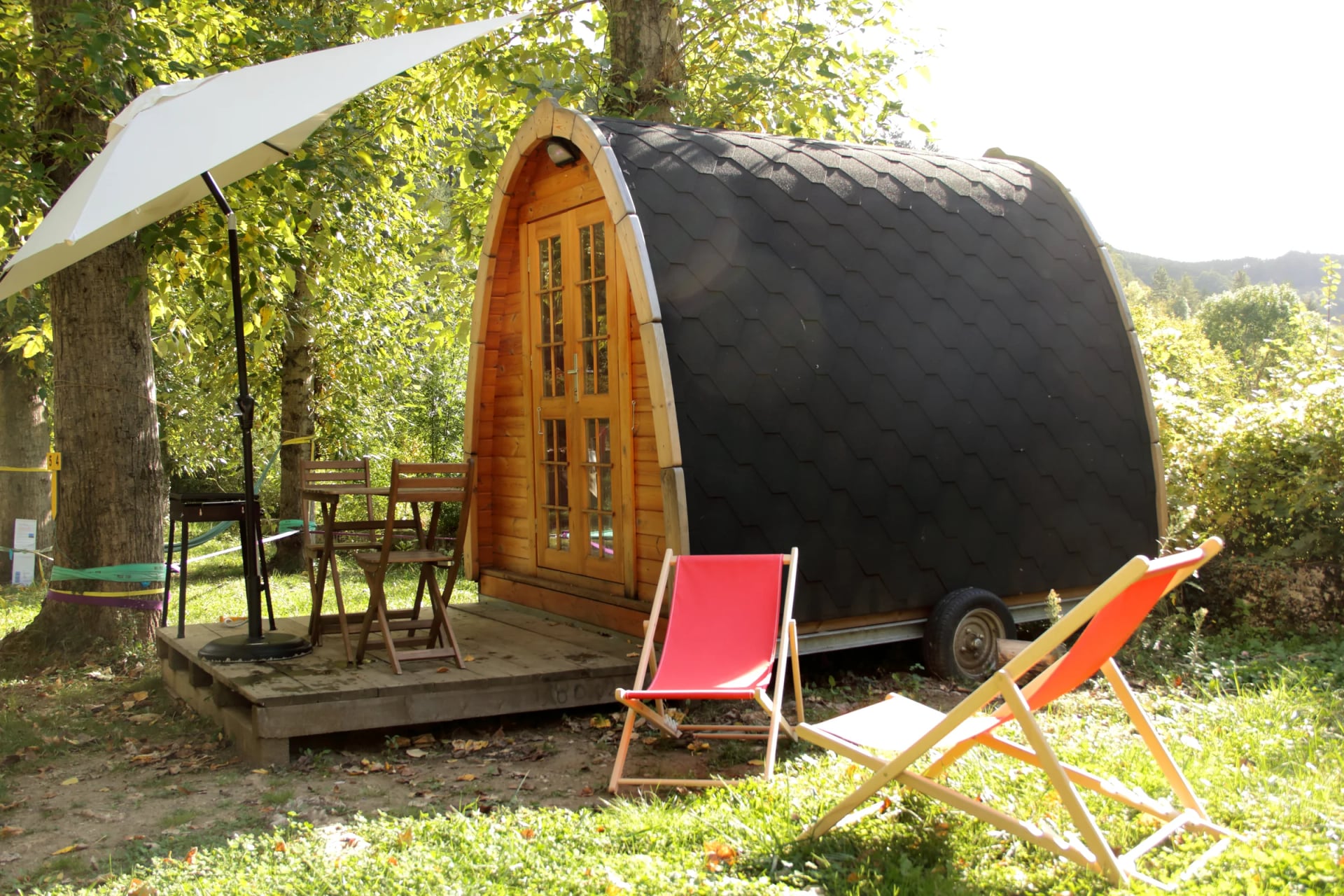 POD met parasol, tafeltje en ligstoelen onder de boom