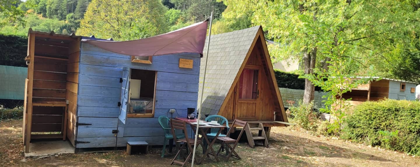 De bedstede met het A-frame-huisje en een gedekte tafel onder het schaduwdoek